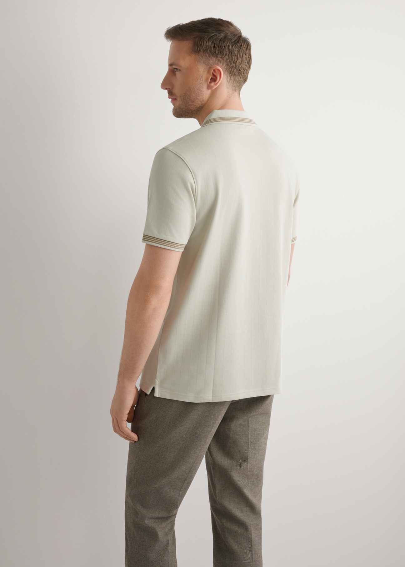 Koszulka polo w kolorze jasnego beżu POLMT-0090-1A(W26), widok produktu z tyłu na modelu. Widoczna połowa sylwetki.
