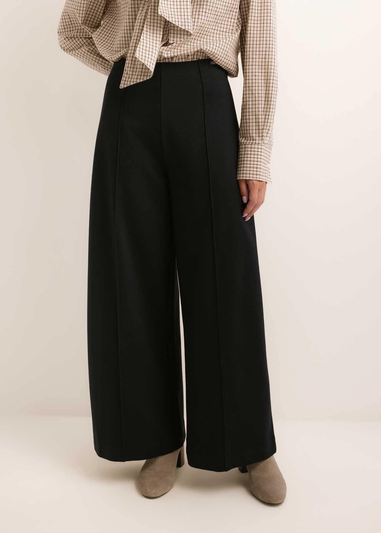 Czarne spodnie damskie wide leg SPODT-0130-99(Z26), widok produktu z przodu na modelce. Widoczna połowa sylwetki.