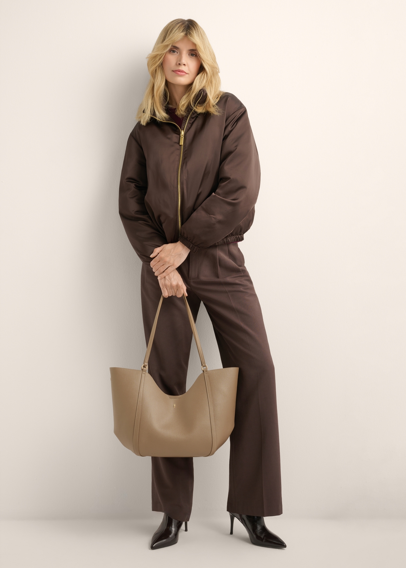 Beżowa torebka damska typu shopper TOREC-1296-1B (Z26), widok produktu w dłoni modelki. Widoczna cała sylwetka.