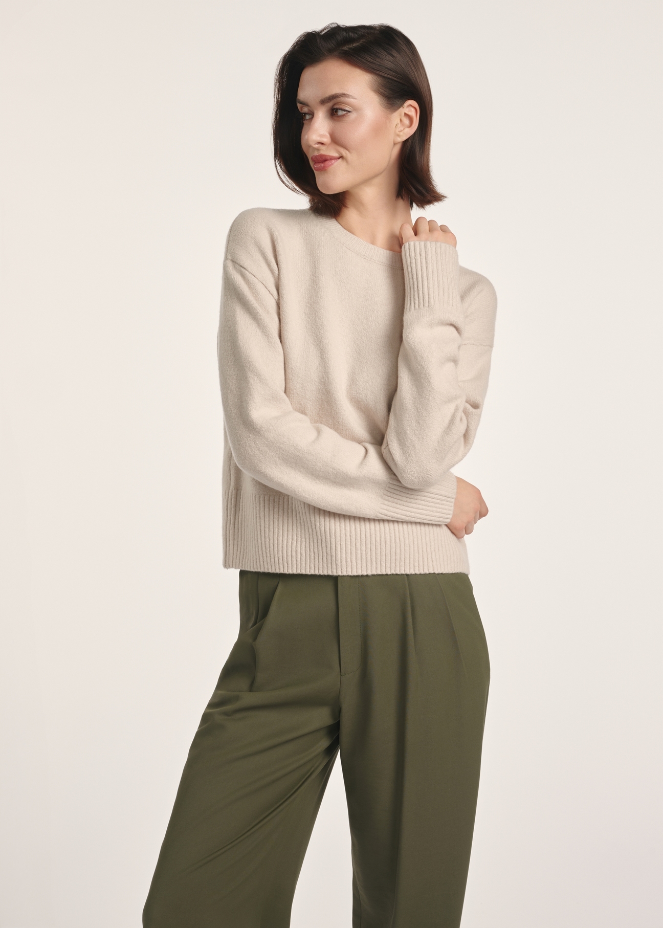 Beżowy sweter damski SWEDT-0242-80(Z25), widok produktu z przodu na modelce. Widoczna połowa sylwetki.