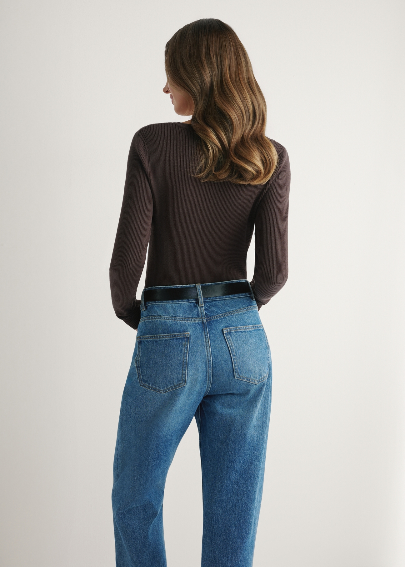 Brązowy prążkowany longsleeve damski LSLDT-0028-1I(W26), widok produktu z tyłu na modelce. Widoczna połowa sylwetki.