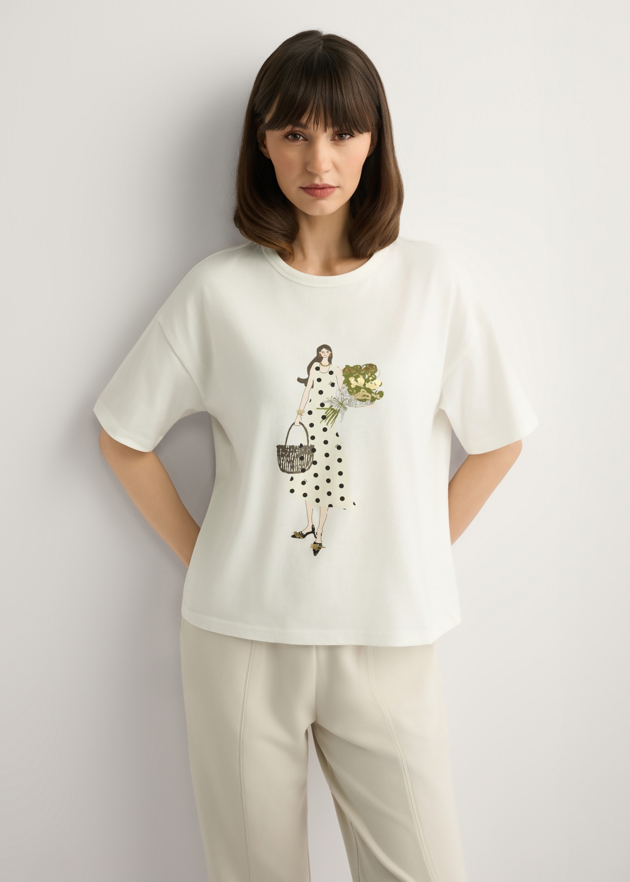 Kremowy T-shirt damski z nadrukiem TSHDT-0161-0B(W26), widok produktu z przodu na modelce. Widoczna połowa sylwetki.