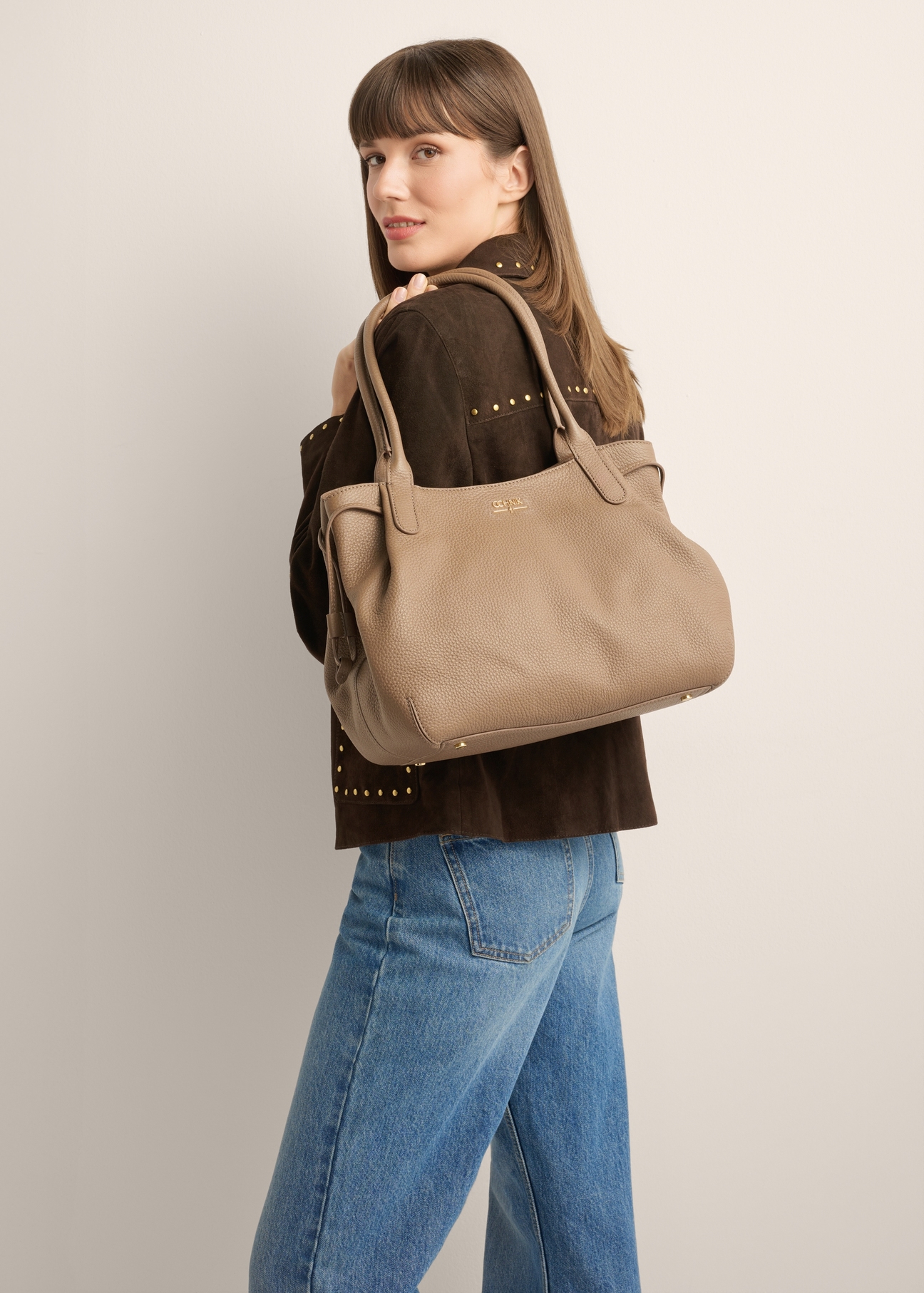 Skórzana torebka shopper w kolorze ciemnego beżu TORES-1360-1K(Z26) - widok produktu z przodu, na modelce, na jasnym tle. Widoczna sylwetka do kolan.