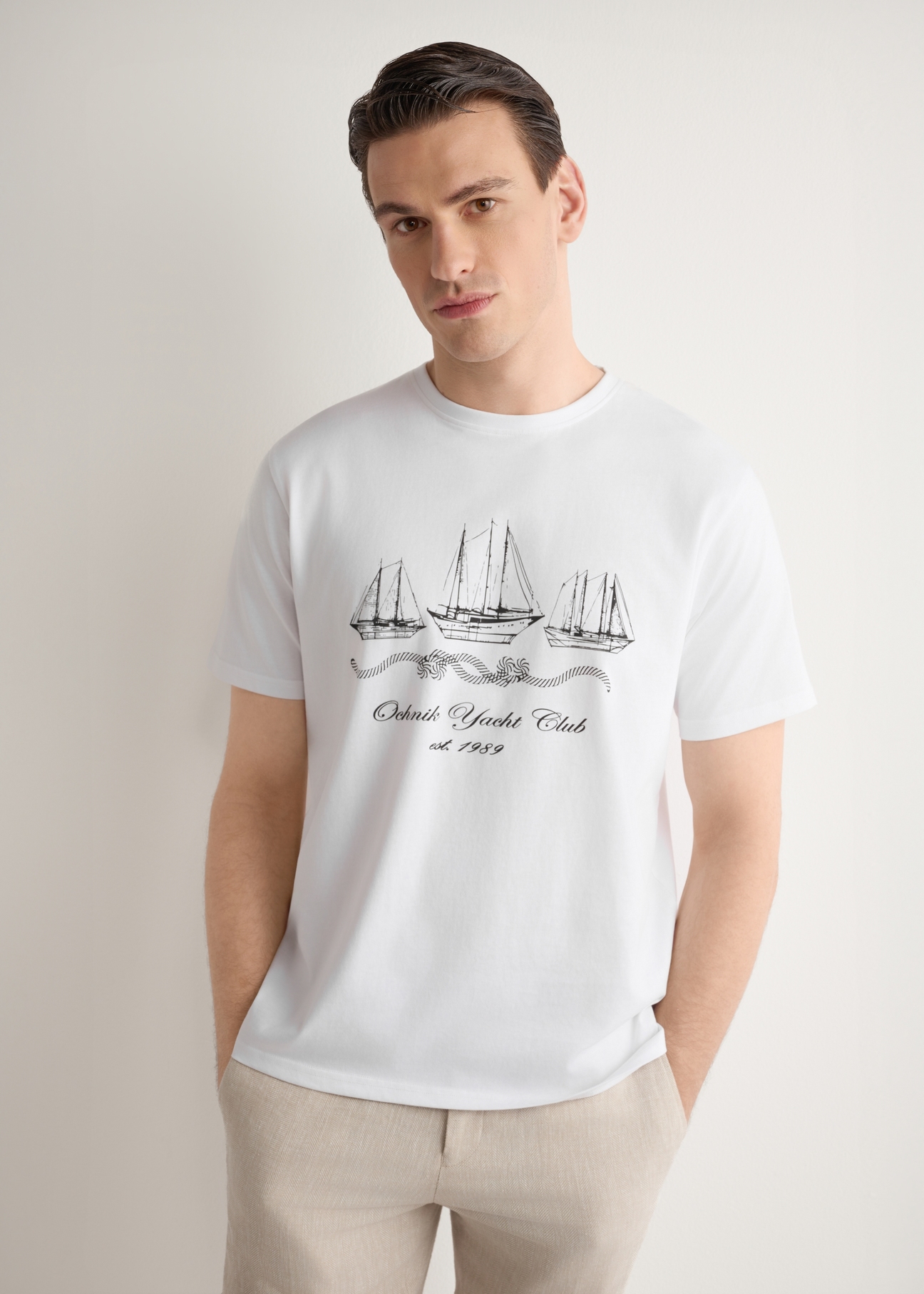 Biały T-shirt męski z nadrukiem TSHMT-0151-0B(W26), widok produktu z przodu na modelu. Widoczna połowa sylwetki.