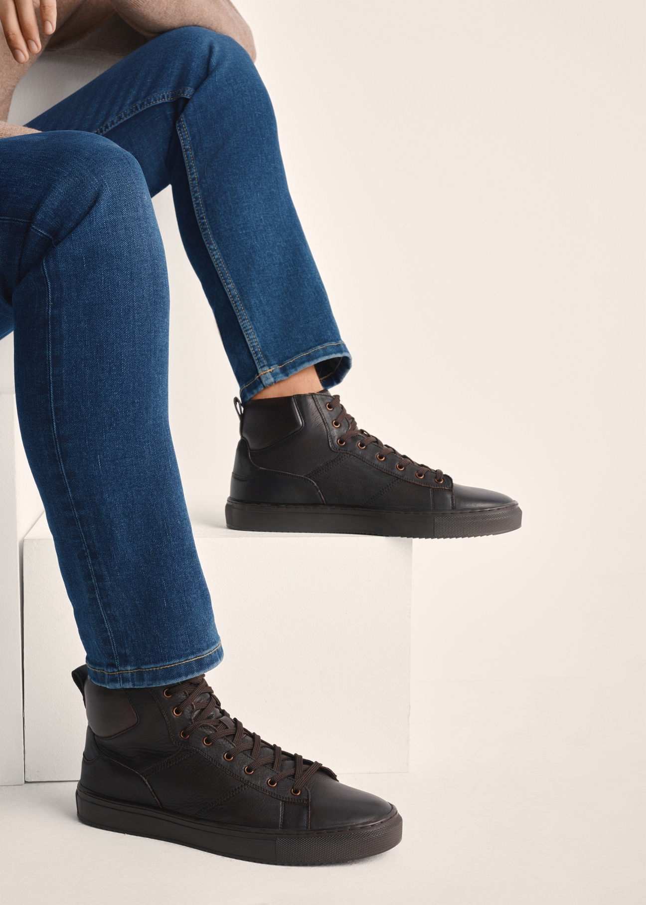 Brązowe skórzane buty sportowe męskie BUTYM-0520-89(Z25) - widok produktu z boku na modelu na białym tle. Widoczna sylwetka do kolan.