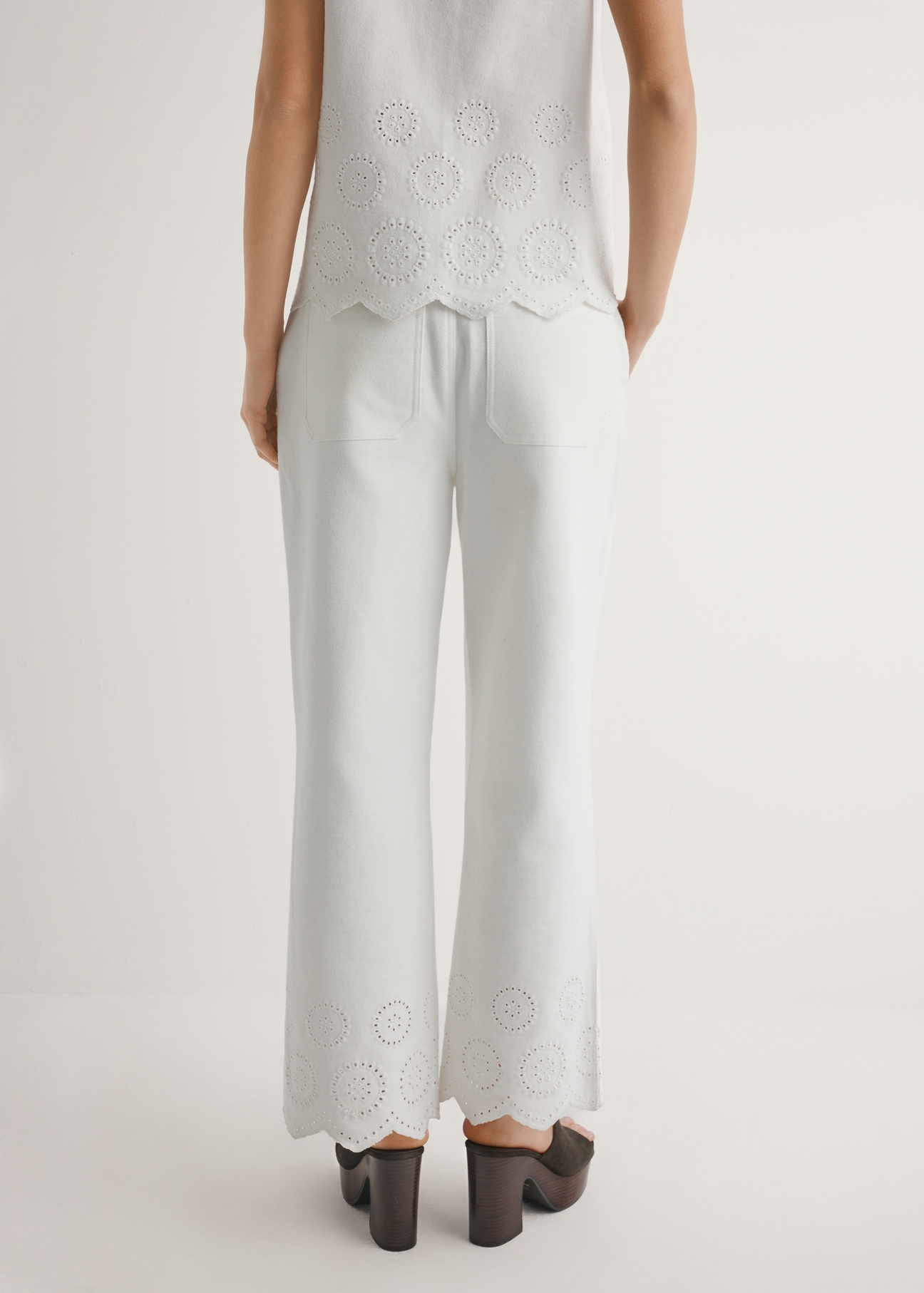 Białe spodnie damskie wide leg SPODT-0122-0B(W26), widok produktu z tyłu na modelce. Widoczna połowa sylwetki.