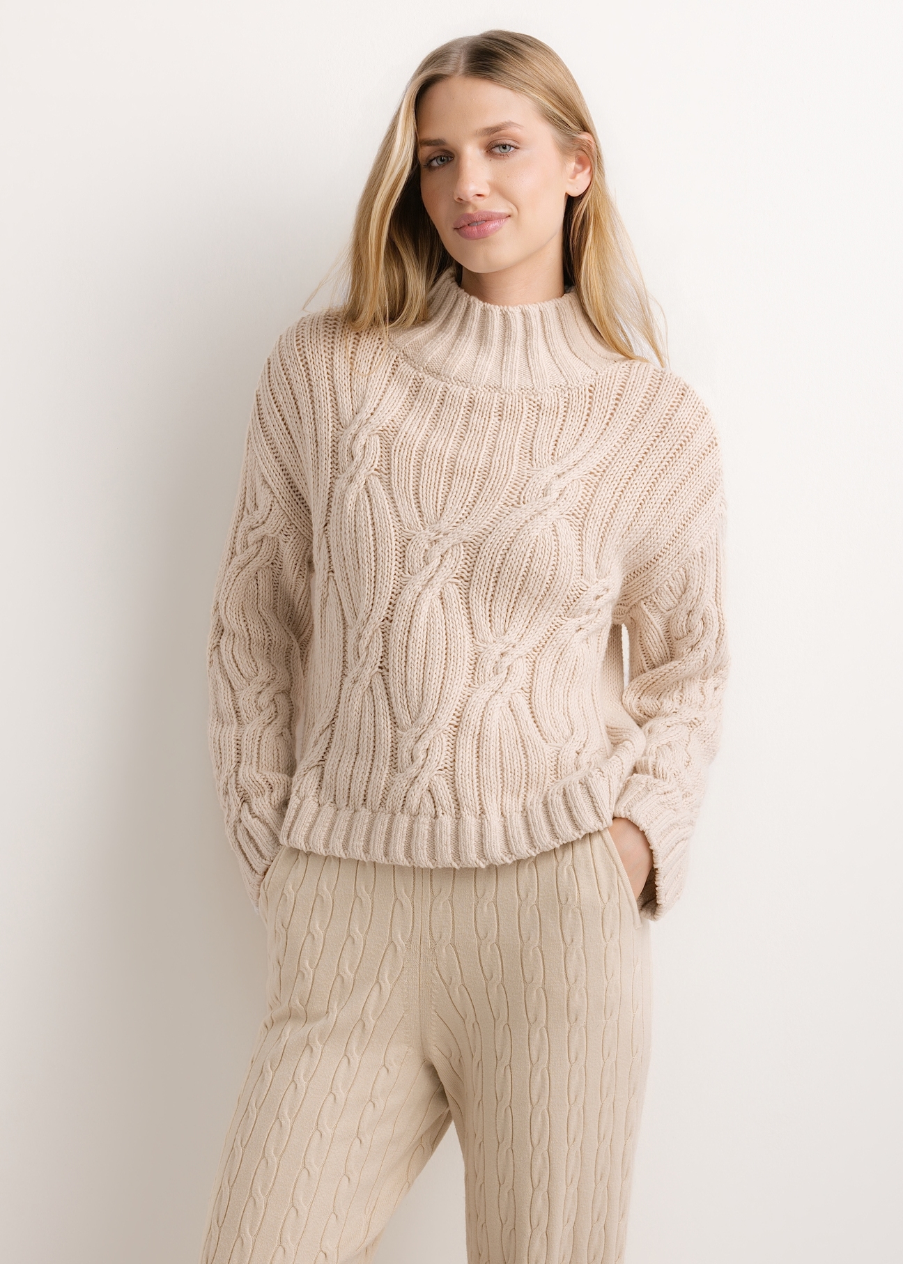 Damski sweter oversize w jasnobeżowym kolorze SWEDT-0278-1A(Z26), widok produktu od przodu na modelce. Widoczna połowa sylwetki.