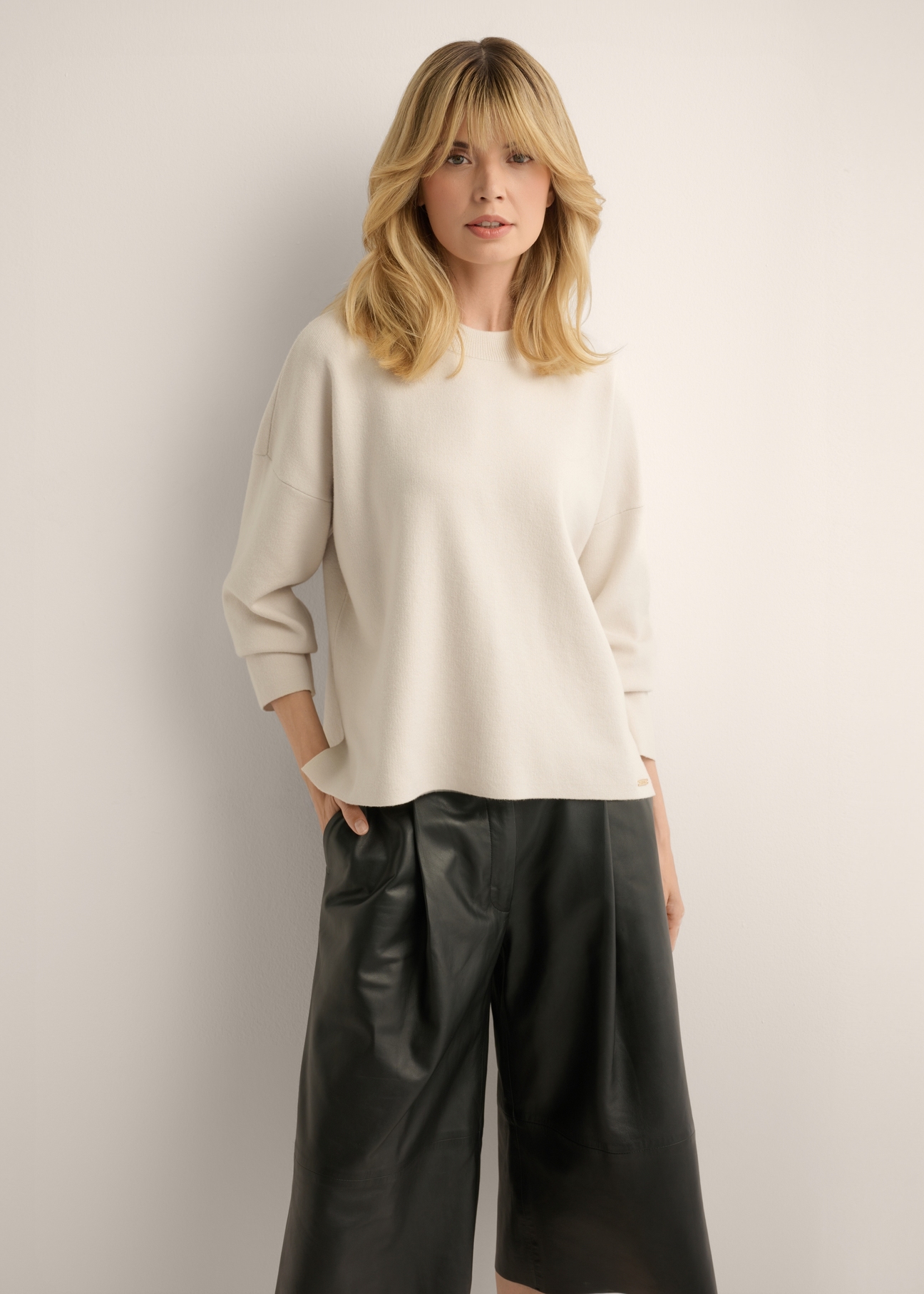 Jasnobeżowy sweter damski SWEDT-0263-1A(Z26), widok produktu z przodu na modelce. Widoczna połowa sylwetki.