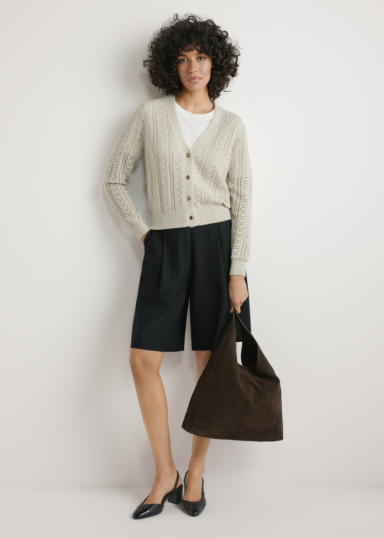 Skórzana torebka shopper w kolorze ciemnobrązowym TORES-1307-1I(W26), widok produktu w dłoni modelki. Widoczna cała sylwetka.