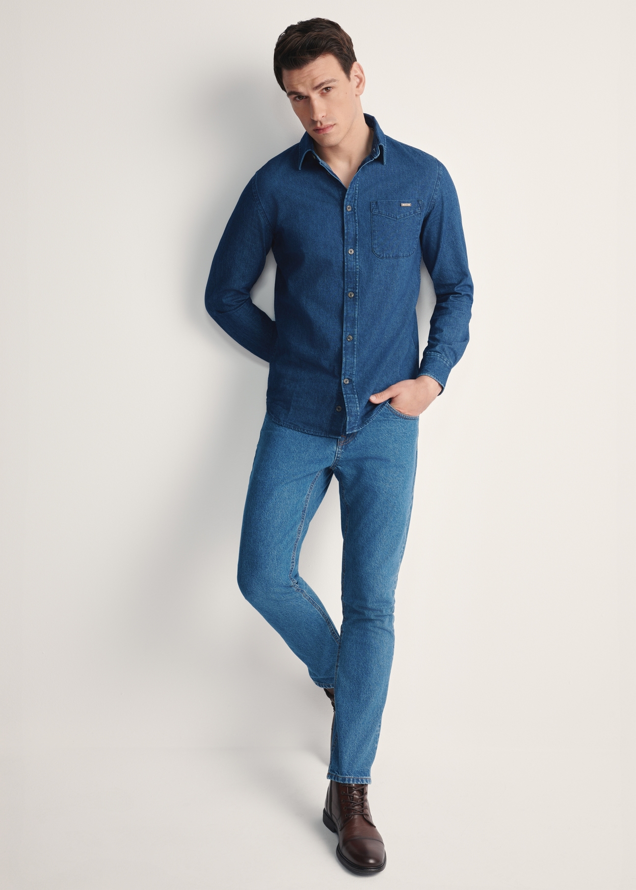Niebieska jeansowa koszula męska KOSMT-0348-61(Z25), produkt widoczny od przodu na modelu, widoczna cała sylwetka.