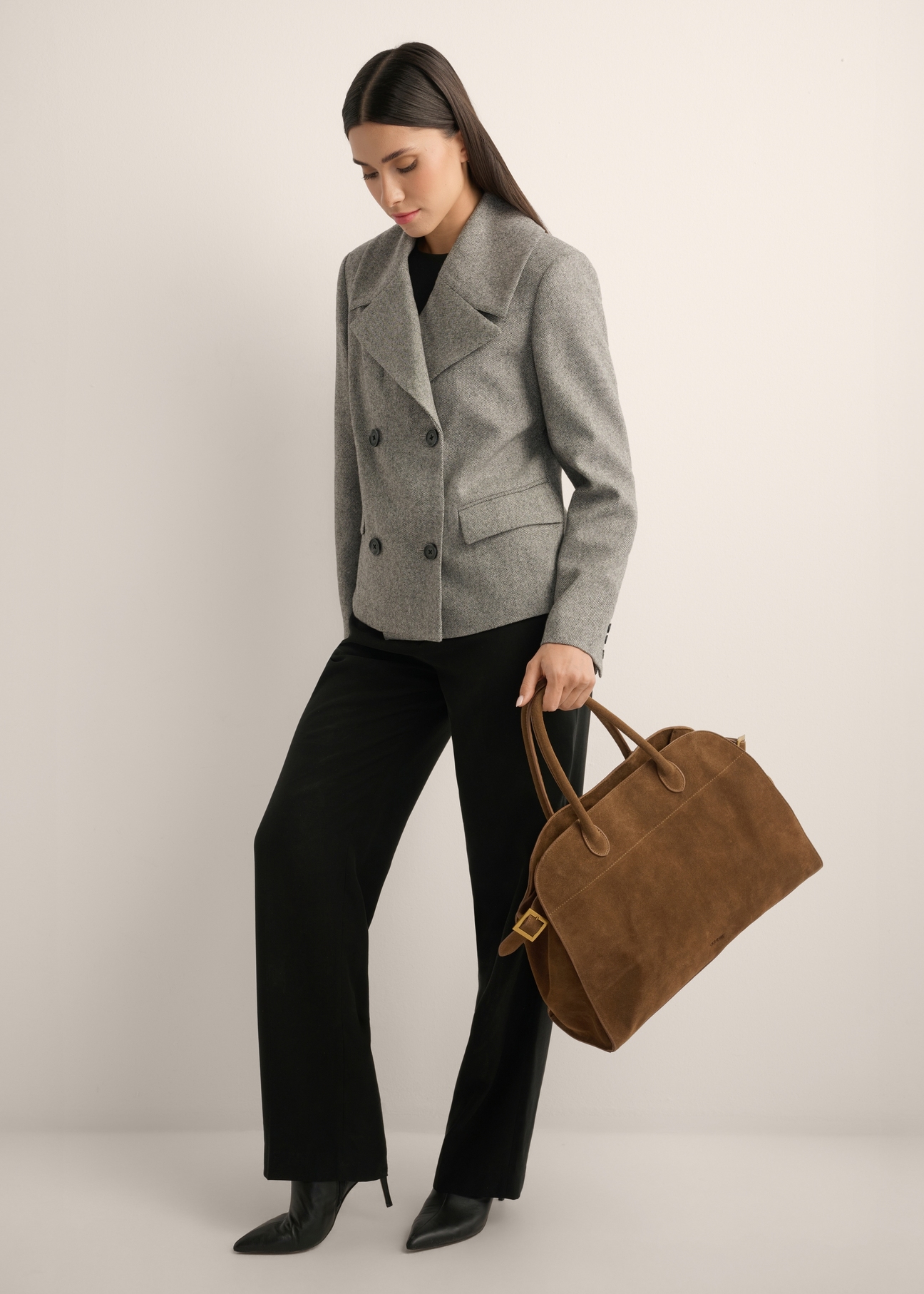 Koniakowa skórzana torebka damska typu shopper TORES-1412-1F(Z26) - widok torebki lekko po skosie, trzymanej przez modelkę w ręku, na jasnym tle. Widoczna cała sylwetka. 
