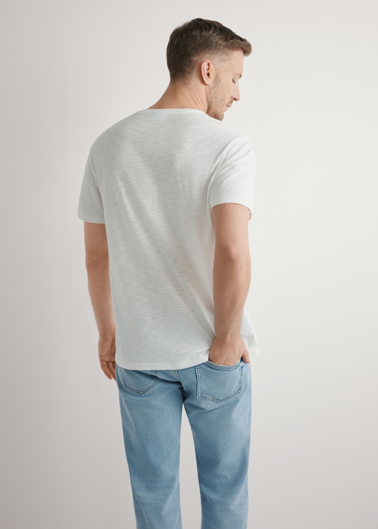 Bawełniany T-shirt męski w kolorze białym TSHMT-0149-0B(W26), widok produktu z tyłu na modelu. Widoczna połowa sylwetki.