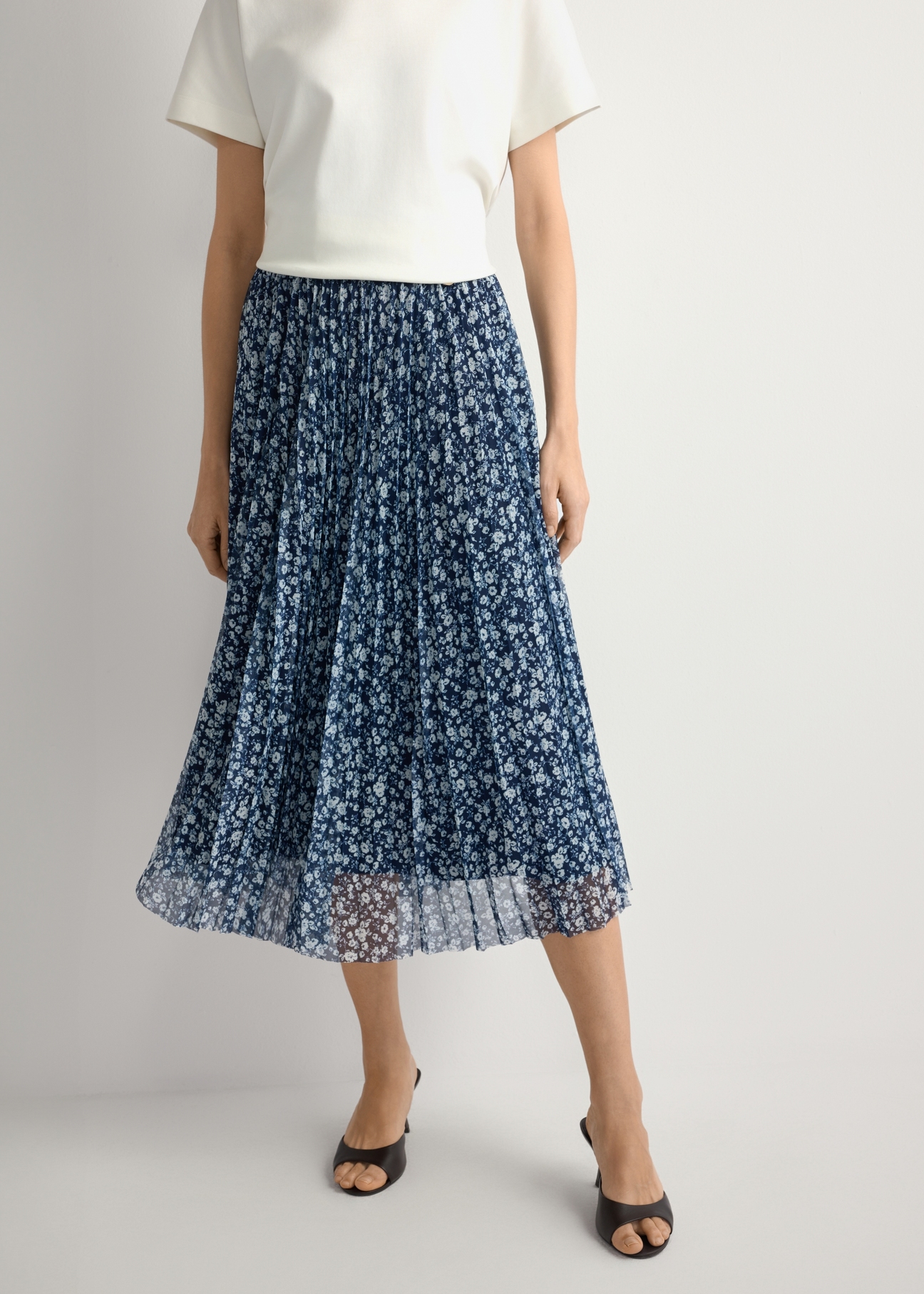 Spódnica plisowana midi w kwiaty SPCDT-0110-7P(W26), widok produktu z przodu na modelce. Widoczna połowa sylwetki.