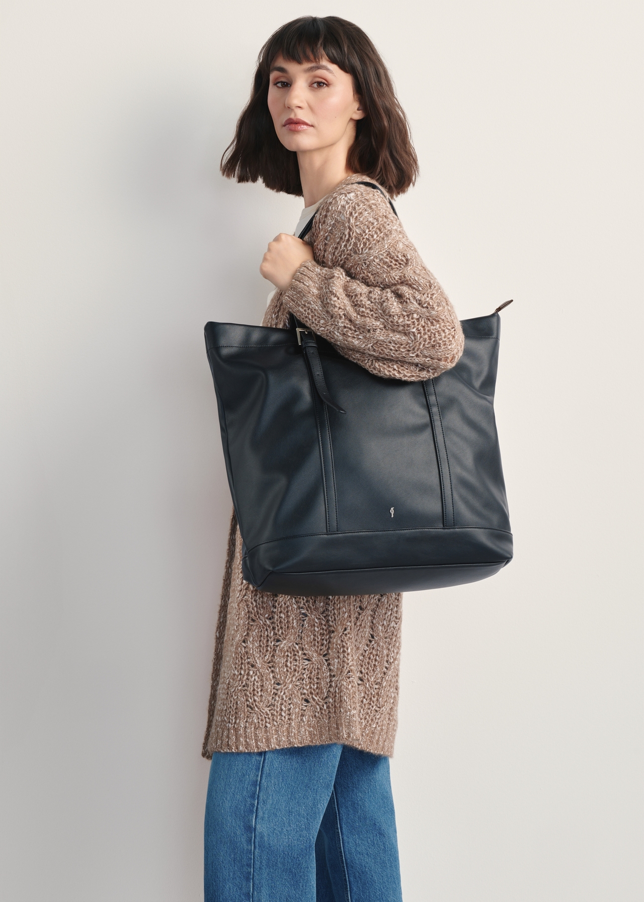 Duża czarna torebka damska shopper TOREC-1067-99(Z25)- widok produktu z przodu na modelce, na białym tle. Widoczna sylwetka do kolan bokiem.