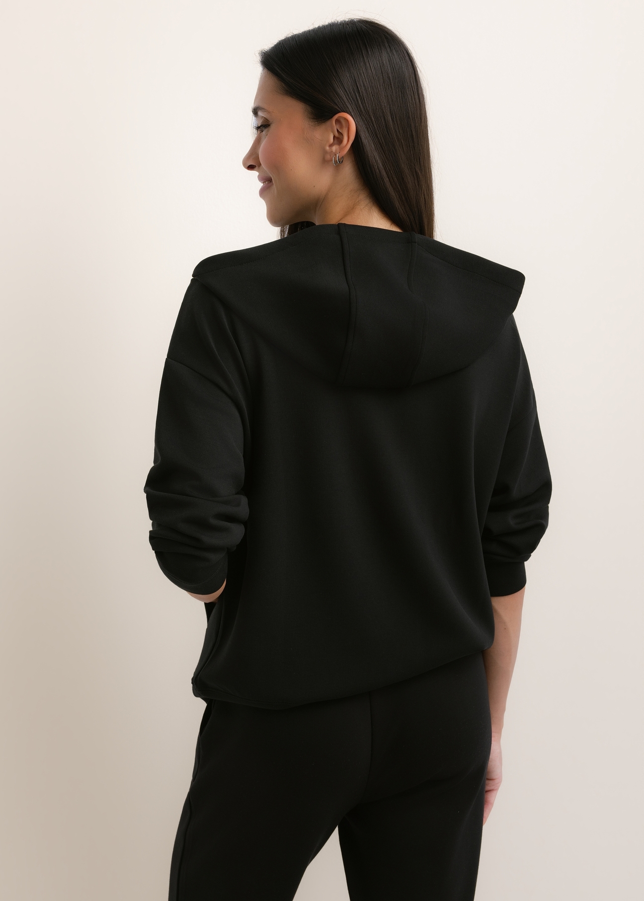 Czarna bluza damska z kapturem BLZDT-0111A-99(W26), widok produktu z tyłu na modelce. Widoczna połowa sylwetki.