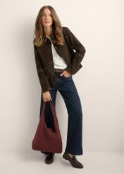 Bordowa zamszowa torebka shopper TORES-1403-4D(Z26) - widok produktu trzymanego przez modelkę w ręku, na jasnym tle. Widoczna cała sylwetka.
