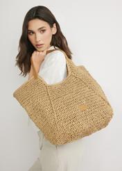 Beżowa słomkowa torebka shopper TOREC-1223-1E(W26) - widok produktu z przodu, na modelce, na jasnym tle. 