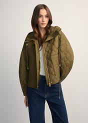 Oliwkowa krótka pikowana kurtka oversize KURDT-0660-8D(W26) - widok produktu z przodu, na modelce, na jasnym tle. Widoczna połowa sylwetki. 