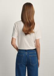 Kremowy T-shirt damski basic TSHDT-0120-0B(W26) - widok produktu z tyłu na modelce, na białym tle. Widoczna sylwetka do kolan. 