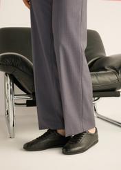 Czarne skórzane sneakersy damskie BUTYD-1293-9I(Z26) - widok produktu z przodu, na stopach modelki, na jasnym tle. 