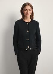 Czarna krótka marynarka damska ZAKDT-0041-99(W26), widok produktu z przodu na modelce. Widoczna połowa sylwetki.