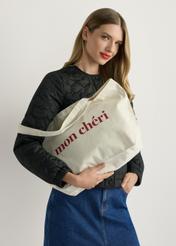 Bawełniana beżowa torebka shopper TOREN-0334-0P(W26), widok produktu w dłoni modelki. Widoczna połowa sylwetki.