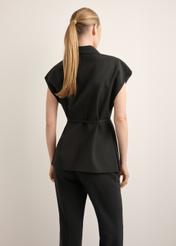 Czarna kamizelka garniturowa damska oversize KAMDT-0039-99(Z26), widok produktu z tyłu na modelce. Widoczna połowa sylwetki.