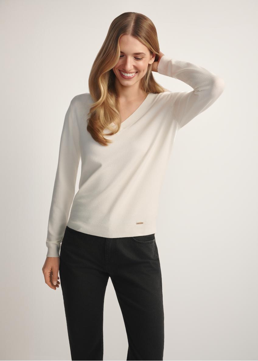 Kremowy sweter z dekoltem V-neck SWEDT-0201-0B(W26), widok produktu z przodu na modelce. Widoczna połowa sylwetki.